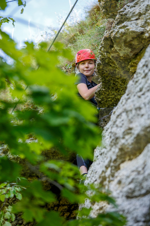 Photo of girl climber in red helmet on mountainの写真素材
