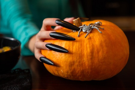 Photo of mans hands with pumpkin jack , spider sitting at wooden tableの写真素材