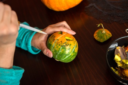 Woman hand in turquoise blouse with pumpkin and knifeの写真素材