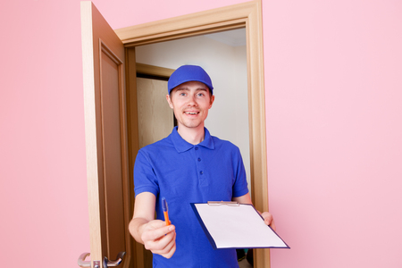 Courier with pen, blank sheet of paper, cardboard boxの写真素材