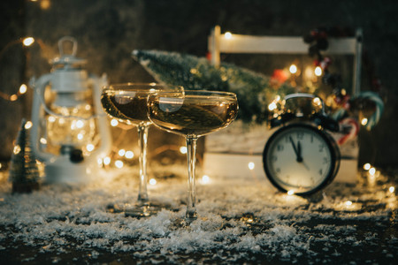 Photo of two champagne glasses on blurred background with Christmas tree, lantern, clock
