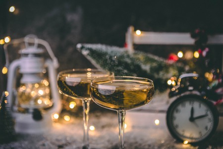 Photo of two wine glasses on blurred background with Christmas tree, lantern, clockの写真素材