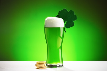 Glass of fresh cold green beer on a wooden bar counter in pub.の写真素材