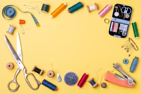 Composition with threads and sewing accessories - scissors, centimeter, pins on yellow background.の写真素材