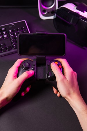 Man hands playing a computer game with a game joystick. Gamer workspace concept.の写真素材