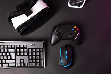 Top view a gaming gear, mouse, keyboard, joystick, headset, VR Headset on black table background. Gamer workspace concept.の写真素材