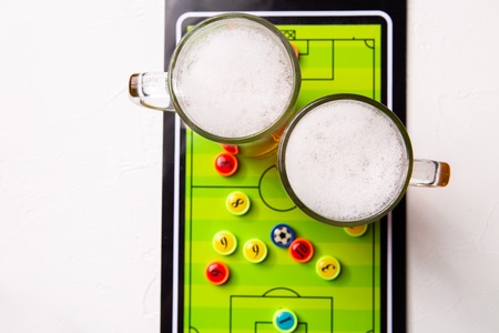 Image on top of two mugs of frothy beer, table footballの写真素材