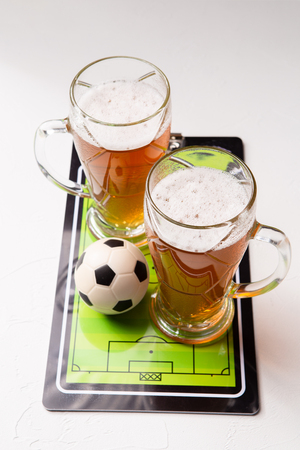 Photo on top of two mugs of frothy beer, table football, ballの写真素材