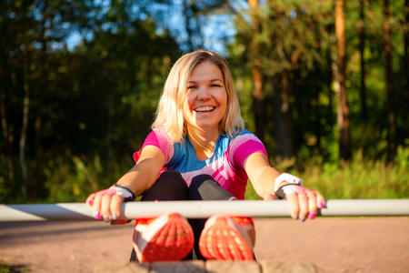 Happy blonde women practicing on wooden bench in park on summer.