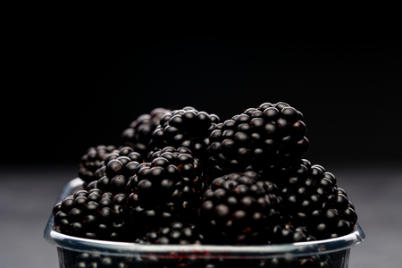 Photo of blackberry in plastic container on empty blackの写真素材