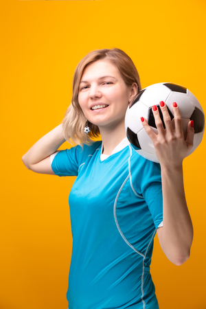 Photo of blonde with soccer ball on yellowの写真素材