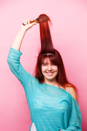 Woman brushing her hair on pink backgroundの写真素材
