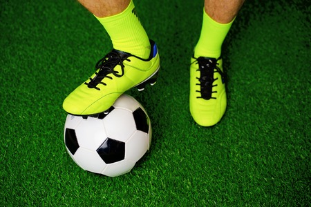 Soccer shoes and football on the green grassの写真素材