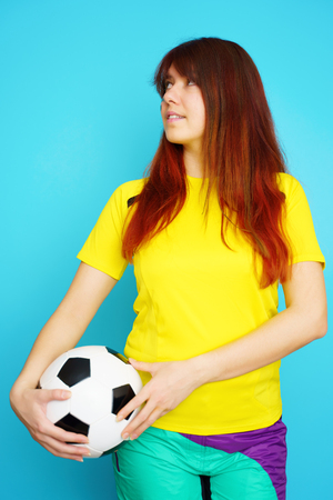 Woman is socccer fan in yellow t-shirt with soccer ballの写真素材