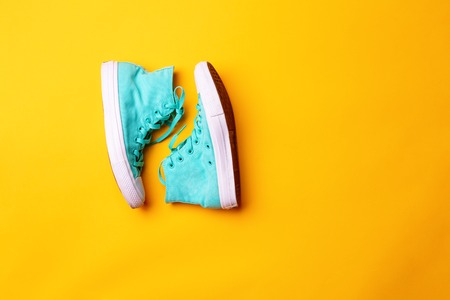 Pair of stylish sneakers laing on yellow background