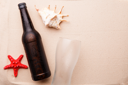 Beer bottle and glass on a sandy beach.の写真素材