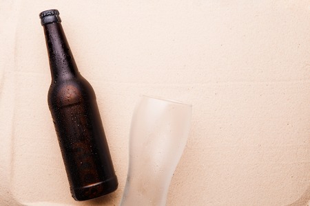 Beer bottle and glass on a sandy beach.の写真素材