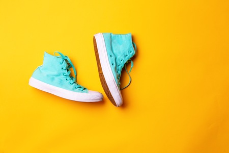 Pair of stylish sneakers laing on yellow backgroundの写真素材