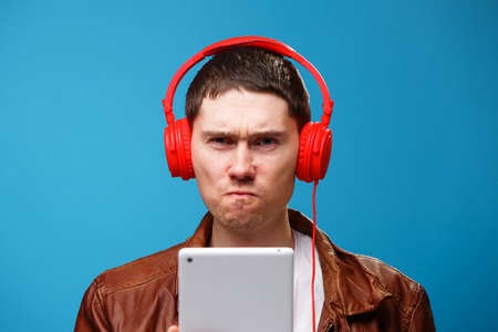 Man is using tablet computer and listening to music with headphones.