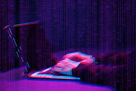 Hacker working with laptop in dark room with digital interface around. Image with glitch effect.の写真素材