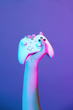 Hand with white gamepad on violet background.の写真素材