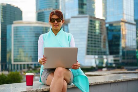 Portrait of business woman sitting with laptop and cup of coffeeの写真素材