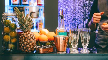 Photo of bar with pineapple, oranges, wine glasses on blurred backgroundの写真素材