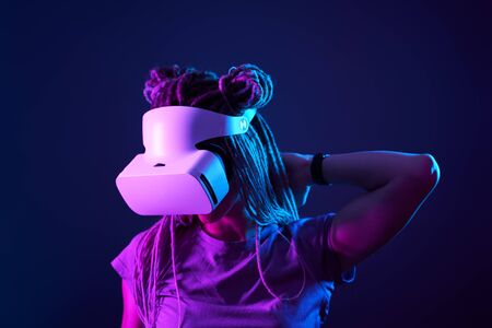 Woman is using virtual reality headset. Neon light studio portrait.の写真素材