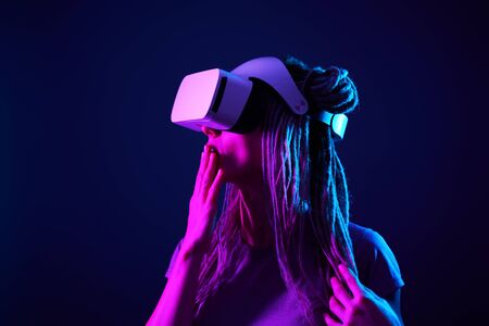 Woman is using virtual reality headset. Neon light studio portrait.