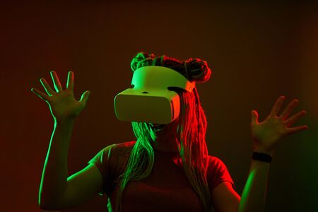 Woman is using virtual reality headset. Neon light studio portrait.