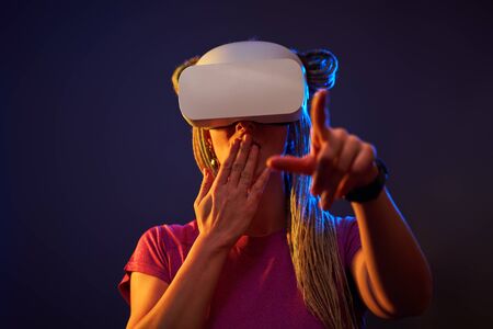 Woman is using virtual reality headset. Neon light studio portrait.