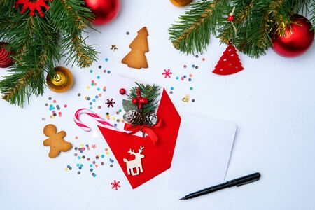 Photo of red envelope, cookies, branches of spruce Christmas decorations on white backgroundの写真素材