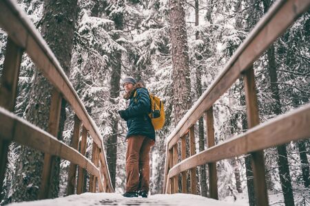 Image of man in winter forest on wooden bridge.の写真素材