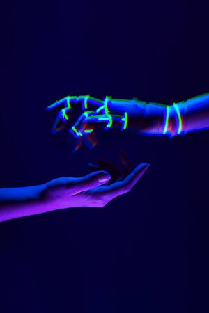 Woman and robots hands as a symbol of connections between people and technology. Neon colors.の写真素材