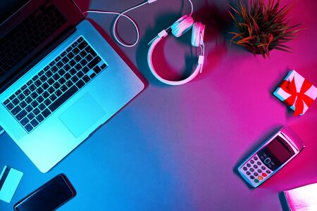 Laptop with headphones, phone, payment card, gift box and pin pad in neon colors. Concept of...