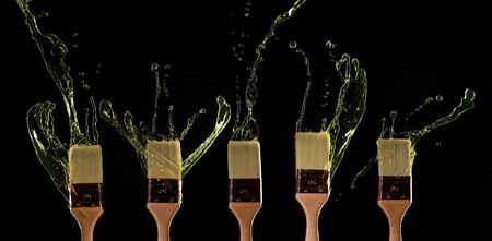 Five brushes with spreading paint on blank black