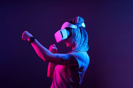 Woman is using virtual reality headset. Neon light studio portrait.の写真素材