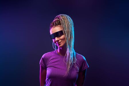 Young girl with pigtails in sunglasses looking at camera in neon lightの写真素材