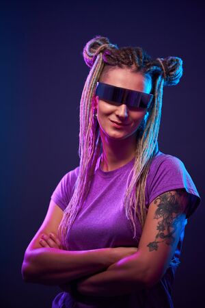 Young girl in sunglasses looking at camera in neon lightの写真素材