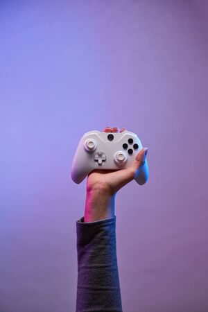 Hand with white gamepad on violet background.