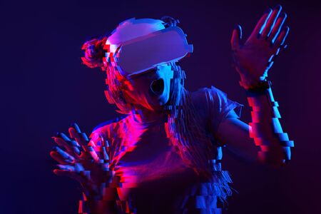 Woman is using virtual reality headset. Neon light studio portrait. Image with glitch effect.の写真素材