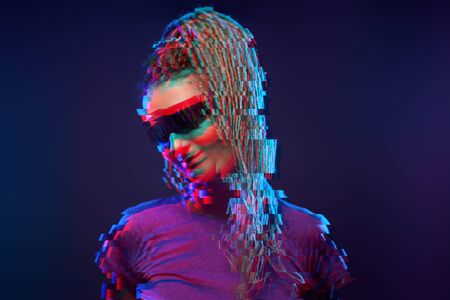 Young girl in sunglasses looking at camera in neon light in studio. Image with glitch effect.の写真素材