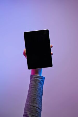 Close-up of mans hand with phone and blank black screen on empty backgroundの写真素材