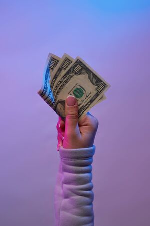 Hand holding banknotes on violet background. Concept of money, business, shopping.