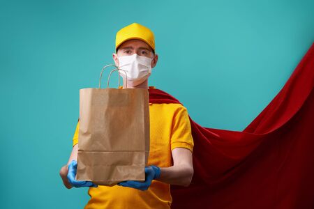 Courier with bag is wearing medical face mask in superhero cloak.の写真素材