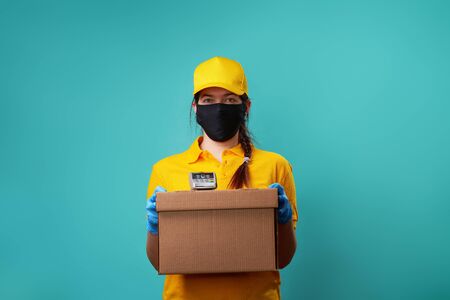 Courier with protected mask on his face holds box and pin pad.の写真素材