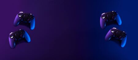 Black gamepads on black background in neon lights.の写真素材