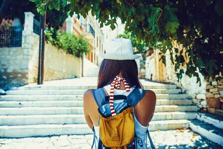 Back side of young traveling woman walking and looking in Greek island of Symi, Dodecanese, Greece.の写真素材