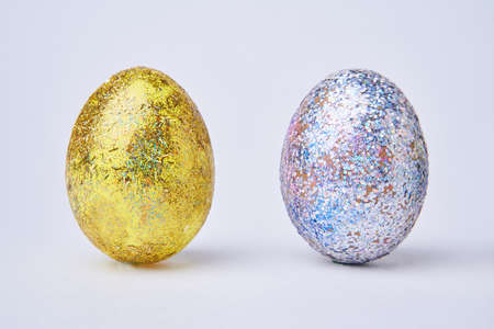 Golden and silver shiny painted eggs on white background.