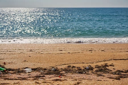 Poured trash on the beach - empty used dirty plastic bottles, packages and other household rubbish.